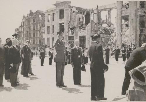 Dépôt de gerbe : le général de Gaulle, saluant, en arrière-plan, les ruines de l'hôtel des postes, juillet 1945 - Archives municipales de Brest, 2 Fi 04936 